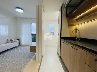 Sala de estar moderna com piso de madeira e cozinha integrada.