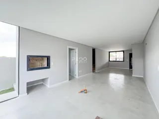 Ambiente interno de uma sala ampla com paredes brancas e piso claro.
