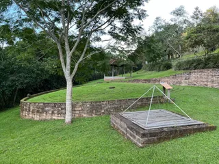 Vista de um jardim com gramado e muro de pedra em uma propriedade.