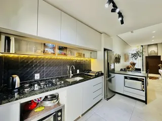 Cozinha moderna com armários brancos e bancada escura.