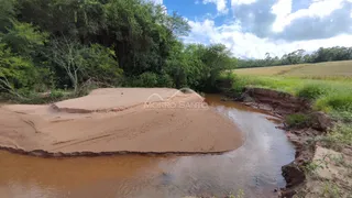 Vista de um rio com margens de terra e vegetação densa ao fundo.