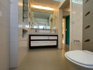 Banheiro com bancada de madeira escura e piso claro.