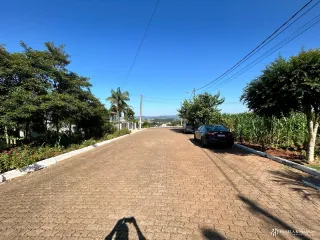 Vista de uma rua pavimentada em Lajeado, Brasil, com vegetação ao redor.