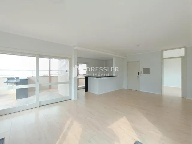 Sala de estar ampla com piso de madeira clara e portas de vidro que dão acesso ao exterior.