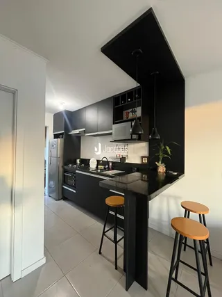 Vista da cozinha moderna com ilha e armários escuros.