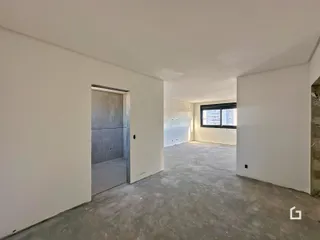 Interior de um cômodo com paredes brancas e piso de concreto aparente.