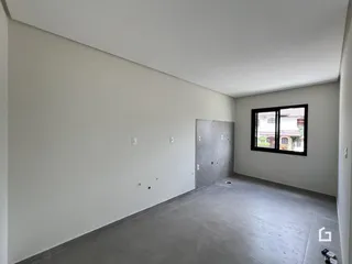 Interior de uma sala com paredes brancas e piso cinza claro.