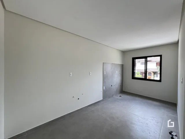 Interior de uma sala com paredes brancas e piso cinza claro.
