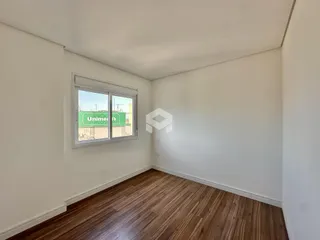 Uma sala com piso de madeira e janela de vista para o exterior.