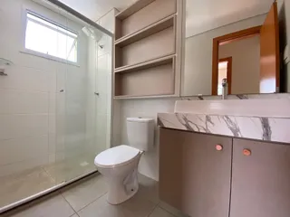 Banheiro com box de vidro e bancada de mármore clara.