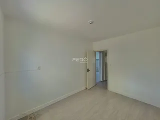 Ambiente interno de uma sala de estar com paredes brancas e piso claro.