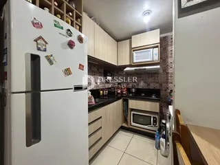 Vista interna de uma cozinha com armários brancos e detalhes em madeira.