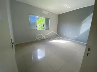 Sala ampla com piso claro e paredes cinzas, com grande janela.