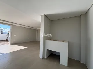 Ambiente interno de uma sala ampla com parede branca e piso claro.
