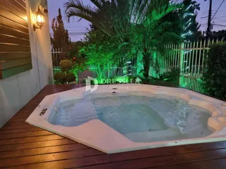 Uma foto de uma piscina com jacuzzi em um deck de madeira ao ar livre.