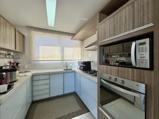 Cozinha moderna com armários e bancadas claras.