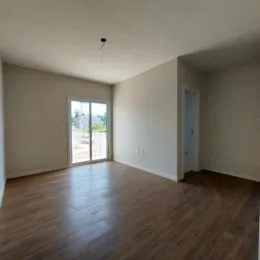 Ambiente interno com piso de madeira e janela iluminada.