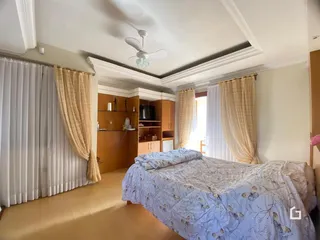 Quarto com cama e cortinas claras.