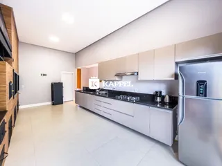 Cozinha moderna com armários claros e bancada escura em um apartamento.
