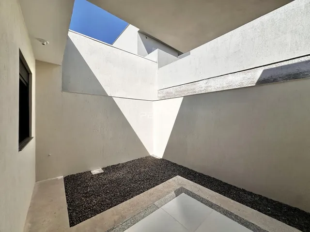 Vista arquitetônica de um espaço interno com paredes brancas e sombras marcantes.