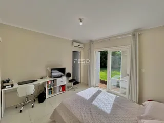 Quarto com cama e espaço de trabalho ao lado de uma porta de vidro.