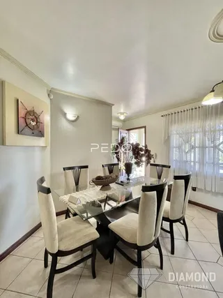 Uma sala de jantar com mesa e cadeiras em um imóvel.