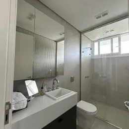 Foto de um banheiro com bancada e vaso sanitário.