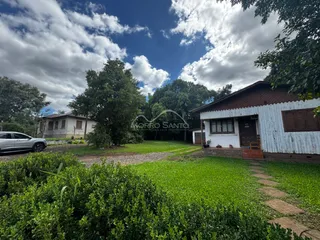 Fachada de uma casa branca com jardim verde em Lajeado.