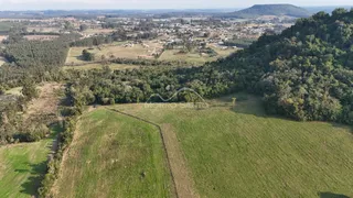 Vista aérea de uma área rural com campos verdes e vegetação densa.