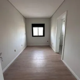 Um corredor interno com piso de madeira clara.