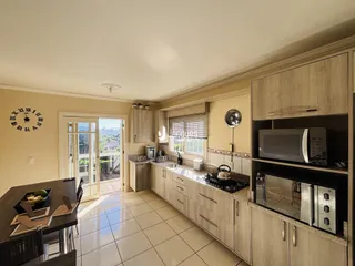 Ambiente interno de sala e cozinha com piso de cerâmica clara.
