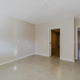 Ambiente interno vazio com paredes brancas e piso claro.