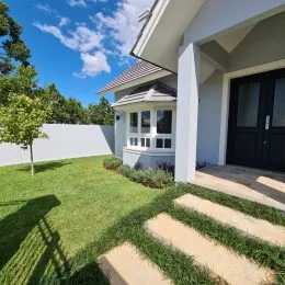 Fachada de uma casa em Lajeado, Brasil, com gramado verde e céu azul.