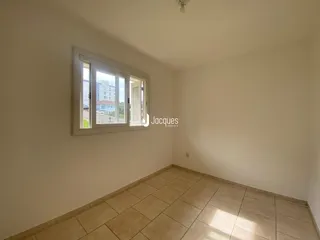 Vista interna de um cômodo com piso de cerâmica e janela.