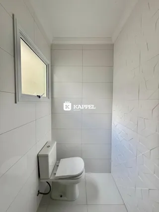 Foto de um banheiro com revestimento branco e vaso sanitário.