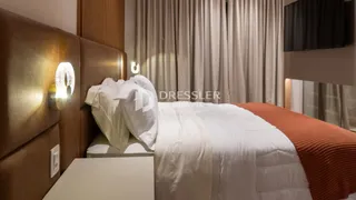 Quarto com cama e cabeceira de madeira em um ambiente claro.