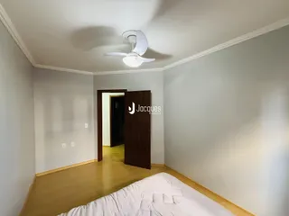 Quarto com piso de madeira clara e teto branco.