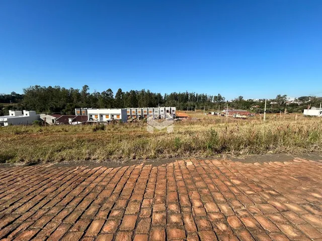 Vista externa de uma propriedade com terreno gramado e edificações ao fundo.