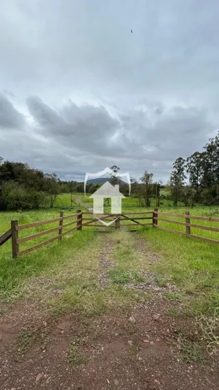 Fachada de uma casa branca em uma área rural com cerca de madeira.