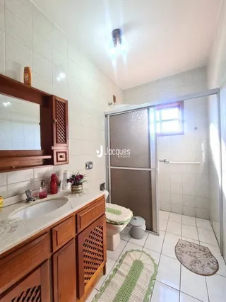 Banheiro com revestimento cerâmico e bancada de madeira.