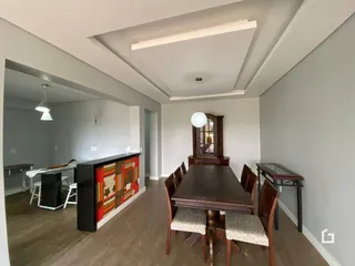 Ambiente interno de sala de jantar com mesa de madeira escura.