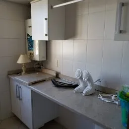 Foto de uma cozinha com armários brancos e bancada clara.