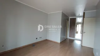 Vista interna de um ambiente com piso de madeira clara e paredes brancas.