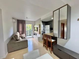 Sala de estar com piso de madeira e grandes janelas em um imóvel no Brasil.