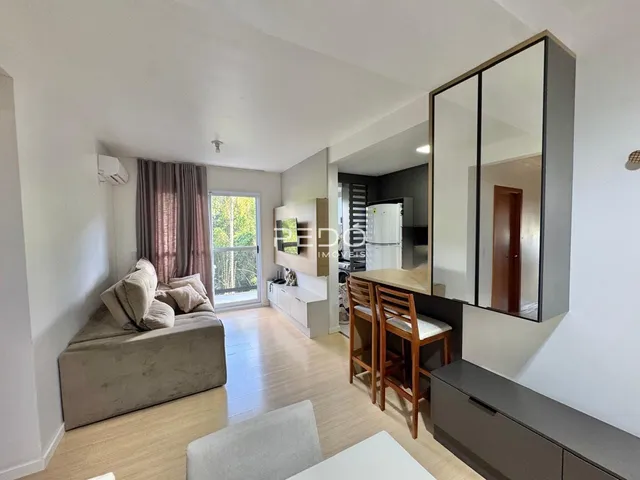 Sala de estar com piso de madeira e grandes janelas em um imóvel no Brasil.