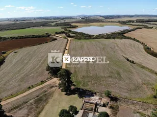 Vista aérea de uma área rural com campos abertos e estradas de terra.