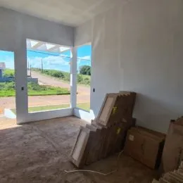 Foto de um cômodo interno com paredes brancas e grandes aberturas para o exterior.