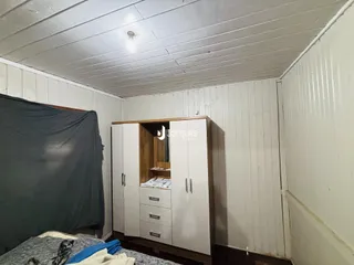 Quarto com painéis brancos e armário de madeira na parede.