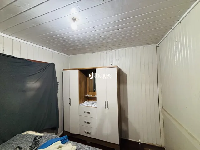 Quarto com painéis brancos e armário de madeira na parede.