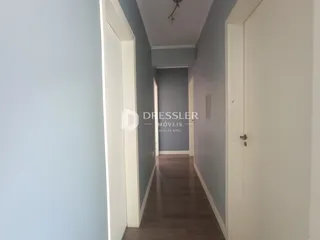 Corredor interno de uma residência com paredes cinza e piso de madeira.